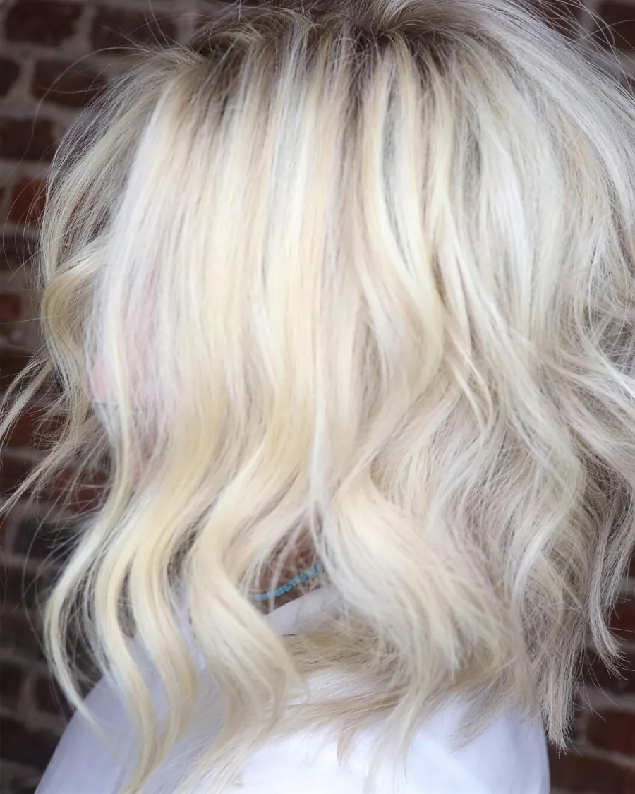 Platinblonde Wellen vor Backsteinwand