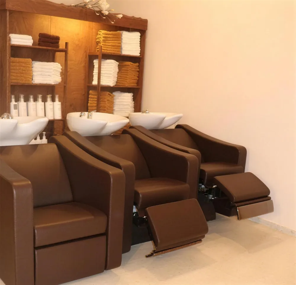 Separater Waschbereich mit drei braunen Massage-Sesseln und Handtuchregal